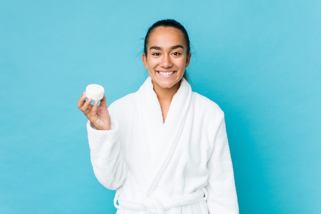 Young mixed race indian holding a moisturizer happy, smiling and cheerful.