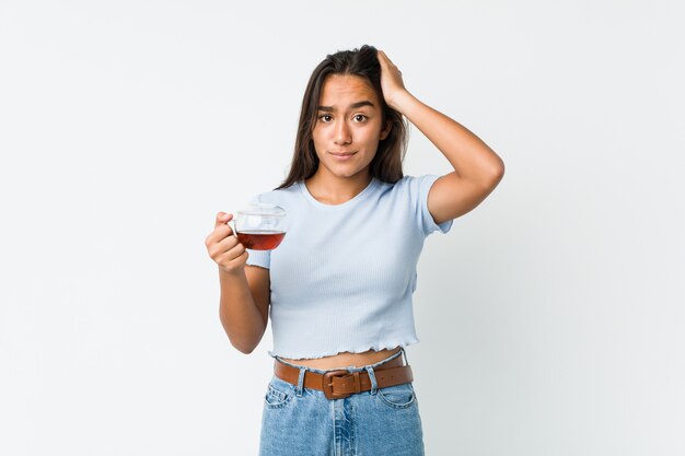 Young mixed race indian holding a tea cup being shocked, she has remembered important meeting.