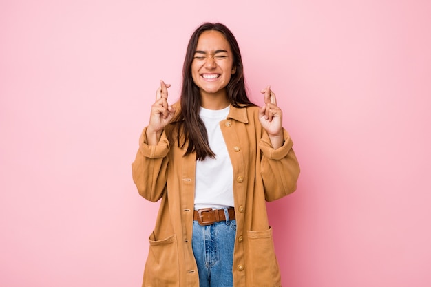 Young mixed race indian woman isolated crossing fingers for having luck