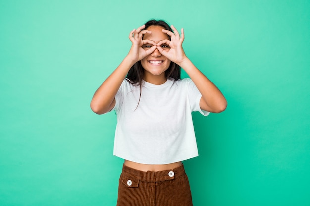 Young mixed race indian woman isolated showing okay sign over eyes