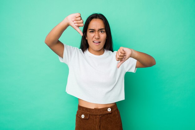 Young mixed race indian woman isolated showing thumb down and expressing dislike.