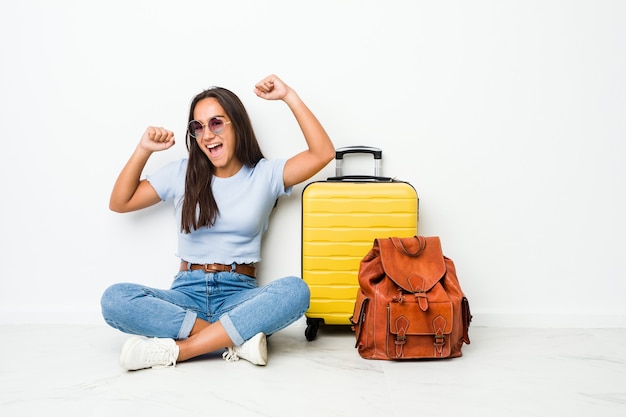 Young mixed race indian woman ready to go to travel celebrating a special day, jumps and raise arms with energy.