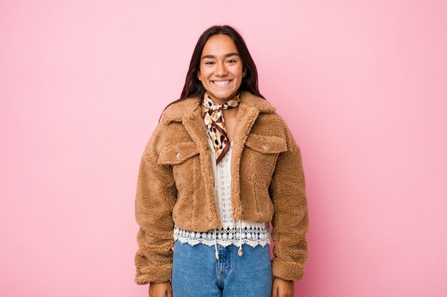 Young mixed race indian woman wearing a short sheepskin coathappy, smiling and cheerful.