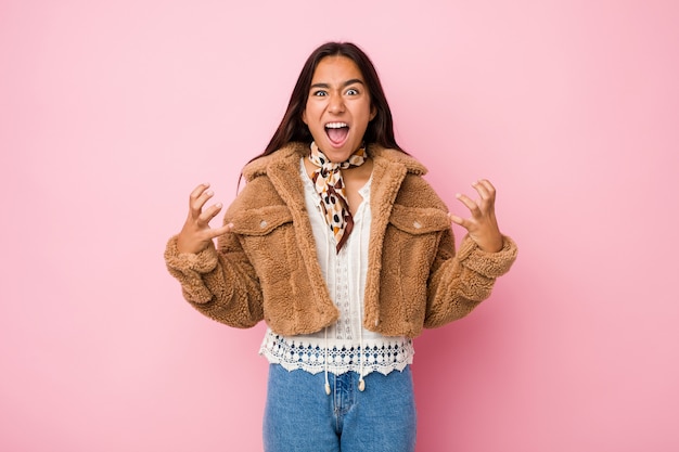 Young mixed race indian woman wearing a short sheepskin coatscreaming with rage.