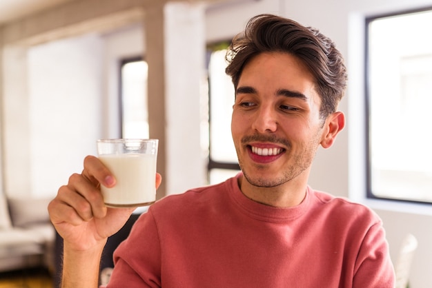 Giovane uomo di razza mista che beve latte a colazione