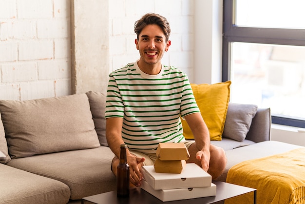 ピザとハンバーガーを食べてビールを飲む若い混血の男