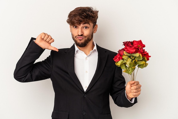 Young mixed race man holding bouquet of roses isolated on white background feels proud and self confident, example to follow.