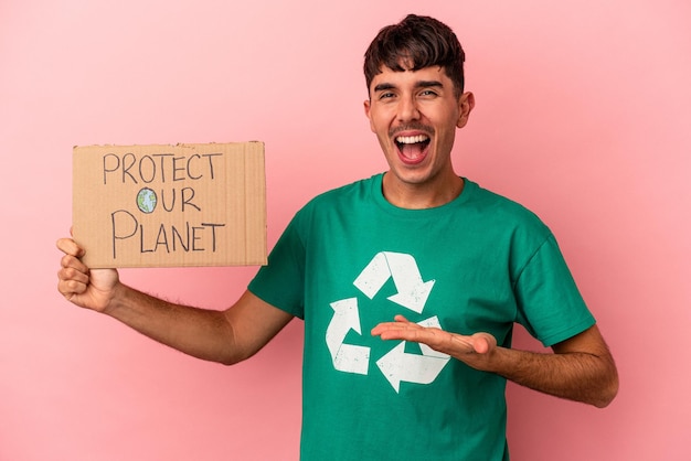 Young mixed race man holding protect your planet placard isolated on pink background