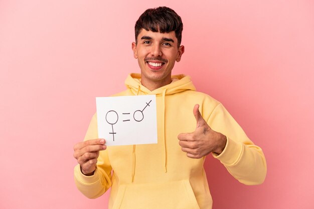 Young mixed race man holding woman and men placard isolated on pink background