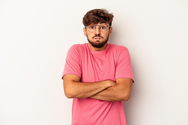 Young mixed race man isolated on grey background blows cheeks, has tired expression. Facial expression concept.