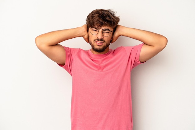 Young mixed race man isolated on grey background covering ears with hands.