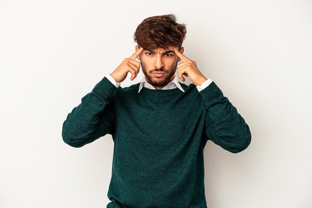 Young mixed race man isolated on grey background focused on a task, keeping forefingers pointing head.