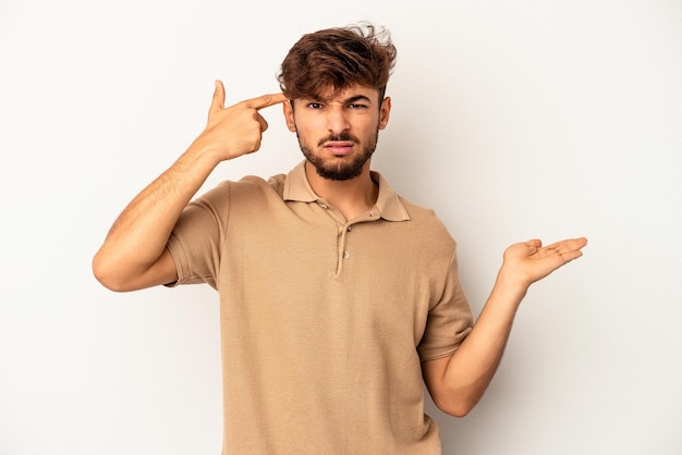 Young mixed race man isolated on grey background holding and showing a product on hand.