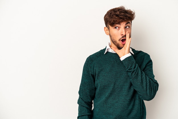 Young mixed race man isolated on grey background is saying a secret hot braking news and looking aside