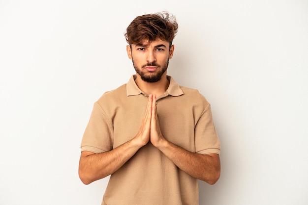 Young mixed race man isolated on grey background praying, showing devotion, religious person looking for divine inspiration.