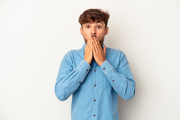 Young mixed race man isolated on grey background shocked covering mouth with hands.