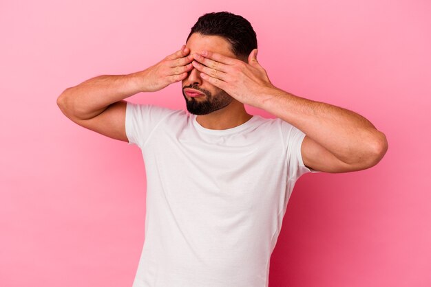 Young mixed race man isolated on pink afraid covering eyes with hands.