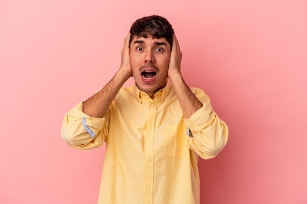 Young mixed race man isolated on pink background being shocked, she has remembered important meeting.