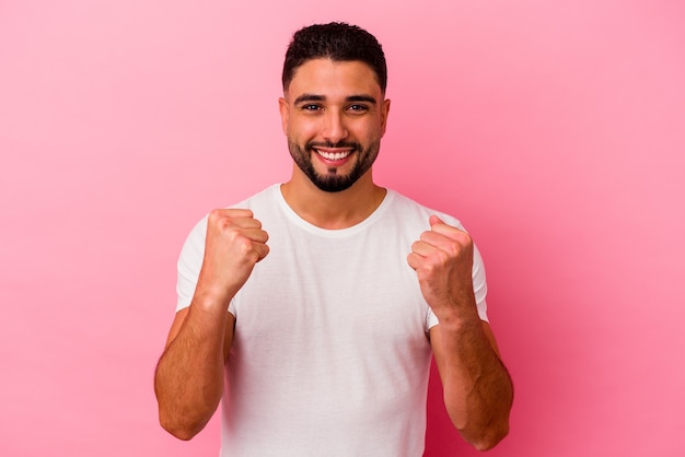 Young mixed race man isolated on pink background cheering carefree and excited. Victory concept.