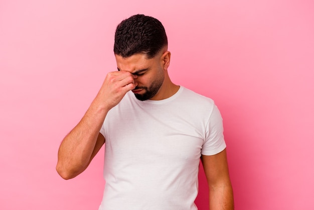 Young mixed race man isolated on pink background having a head ache, touching front of the face.