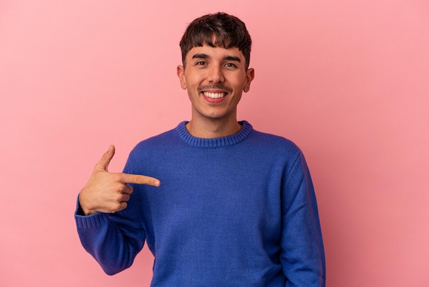 Young mixed race man isolated on pink background person pointing by hand to a shirt copy space, proud and confident