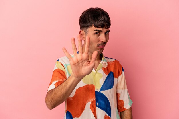 Young mixed race man isolated on pink background rejecting someone showing a gesture of disgust.