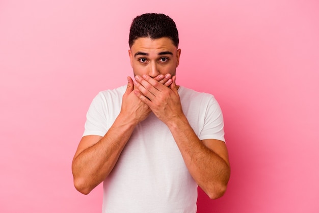 Young mixed race man isolated on pink background shocked, covering mouth with hands, anxious to discover something new.