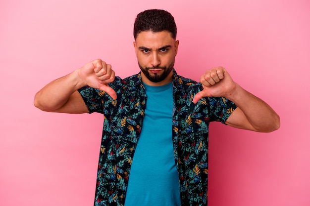 Young mixed race man isolated on pink background showing a dislike gesture, thumbs down. Disagreement concept.