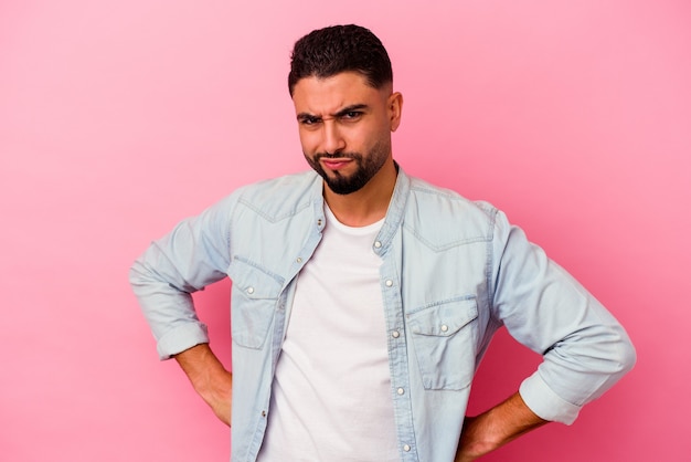 Young mixed race man isolated on pink frowning face in displeasure, keeps arms folded.