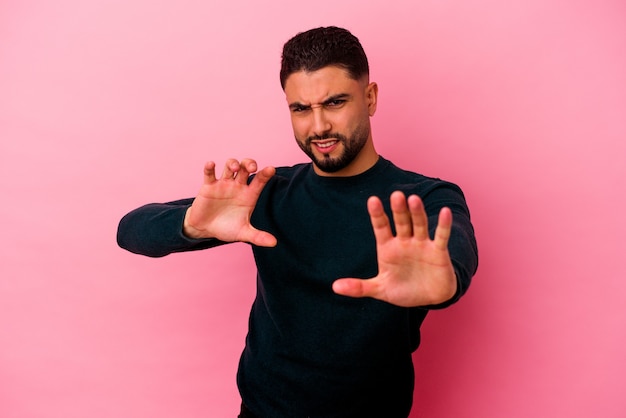 Young mixed race man isolated on pink wall upset screaming with tense hands.