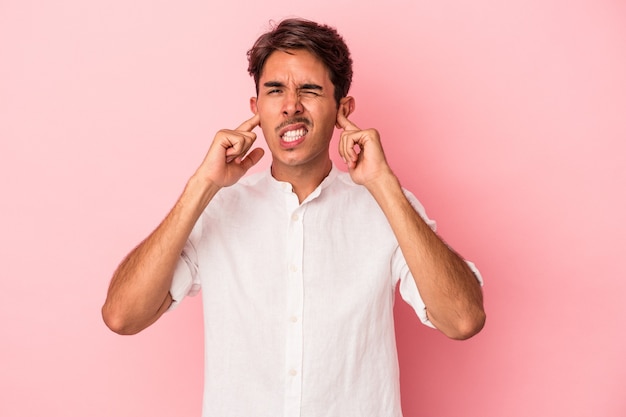 Young mixed race man isolated on white background covering ears with fingers, stressed and desperate by a loudly ambient.