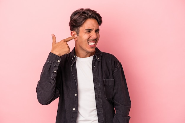 Young mixed race man isolated on white background covering ears with hands.