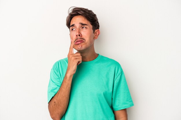 Young mixed race man isolated on white background crying, unhappy with something, agony and confusion concept.