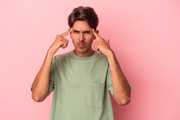 Young mixed race man isolated on white background focused on a task, keeping forefingers pointing head.