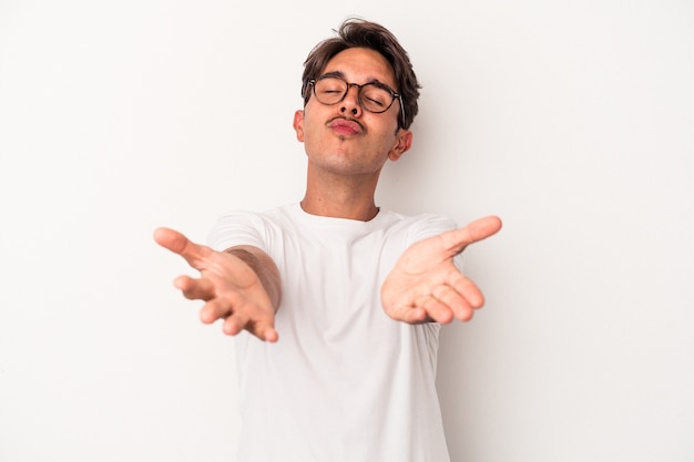 Young mixed race man isolated on white background folding lips and holding palms to send air kiss.