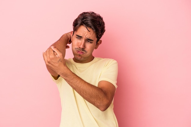 Foto giovane uomo di razza mista isolato su sfondo bianco con un dolore al collo dovuto allo stress, massaggiandolo e toccandolo con la mano.