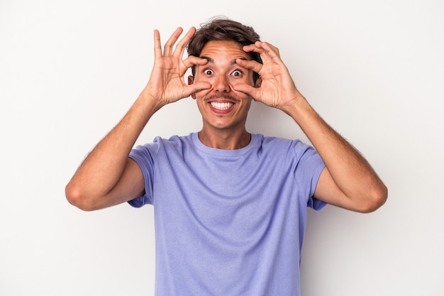 Giovane uomo di razza mista isolato su sfondo bianco tenendo gli occhi aperti per trovare un'opportunità di successo.