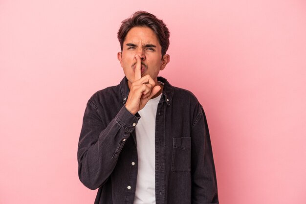 Young mixed race man isolated on white background keeping a secret or asking for silence.