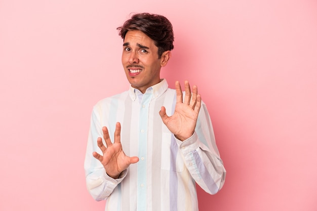 Young mixed race man isolated on white background rejecting someone showing a gesture of disgust.