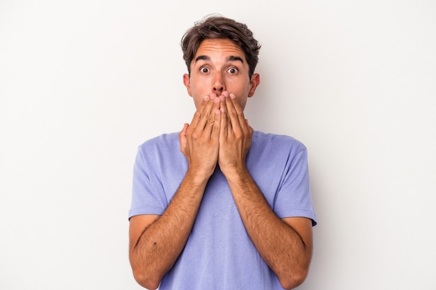 Young mixed race man isolated on white background shocked, covering mouth with hands, anxious to discover something new.