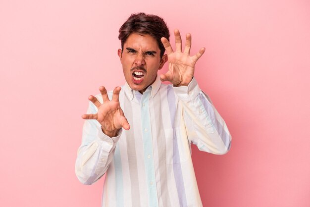 Young mixed race man isolated on white background showing claws imitating a cat, aggressive gesture.