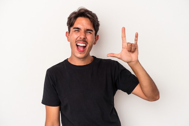 Young mixed race man isolated on white background showing a horns gesture as a revolution concept.