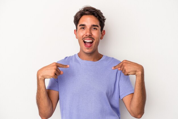 Young mixed race man isolated on white background surprised pointing with finger, smiling broadly.