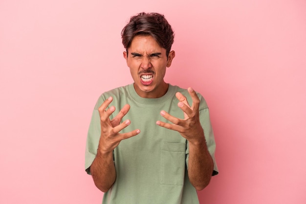 Young mixed race man isolated on white background upset screaming with tense hands.
