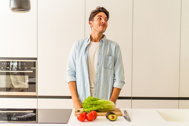 Young mixed race man preparing a salad for lunch dreaming of achieving goals and purposes