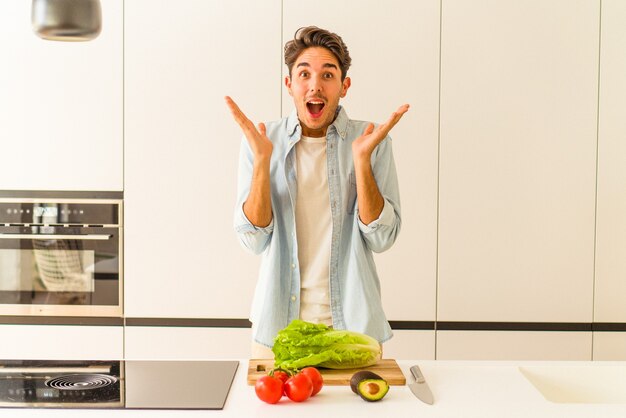 Young mixed race man preparing a salad for lunch surprised and shocked.