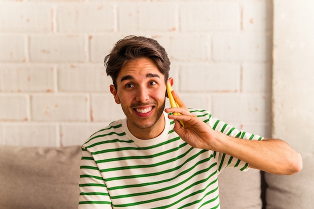 Giovane uomo di razza mista che parla al telefono sul suo divano