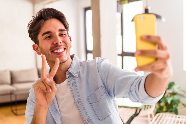 Giovane uomo di razza mista che parla al telefono in cucina