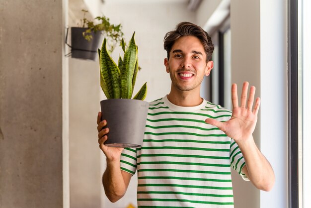 Young mixed race man with a plant in his house