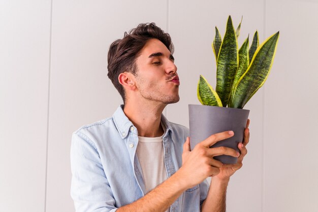 Young mixed race man with a plant in a kitchen